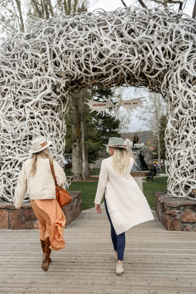 Women walking in front of antler arches.